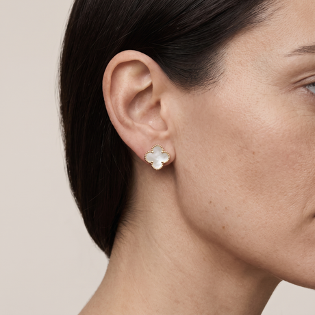A gold-plated mother-of-pearl stud earring worn on an ear
