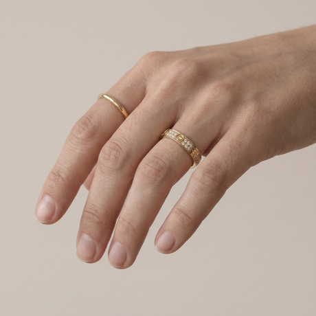 A hand wearing two slim gold-plated rings