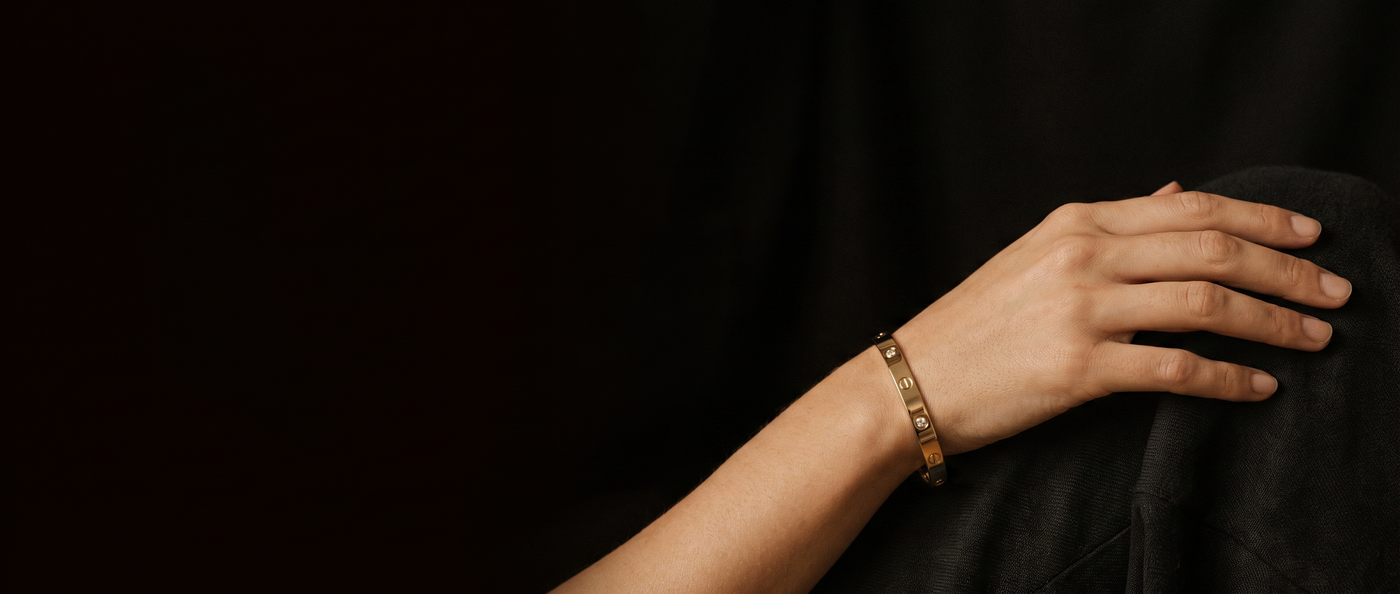 A gold-plated bangle worn on a wrist against a dark background